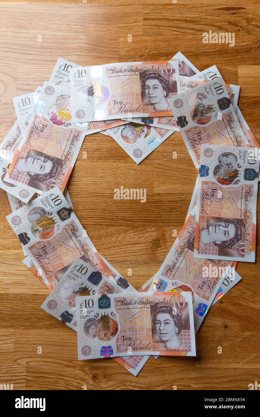 Dieci banconote da libbra a forma di cuore, in contanti sterling britannico Foto Stock