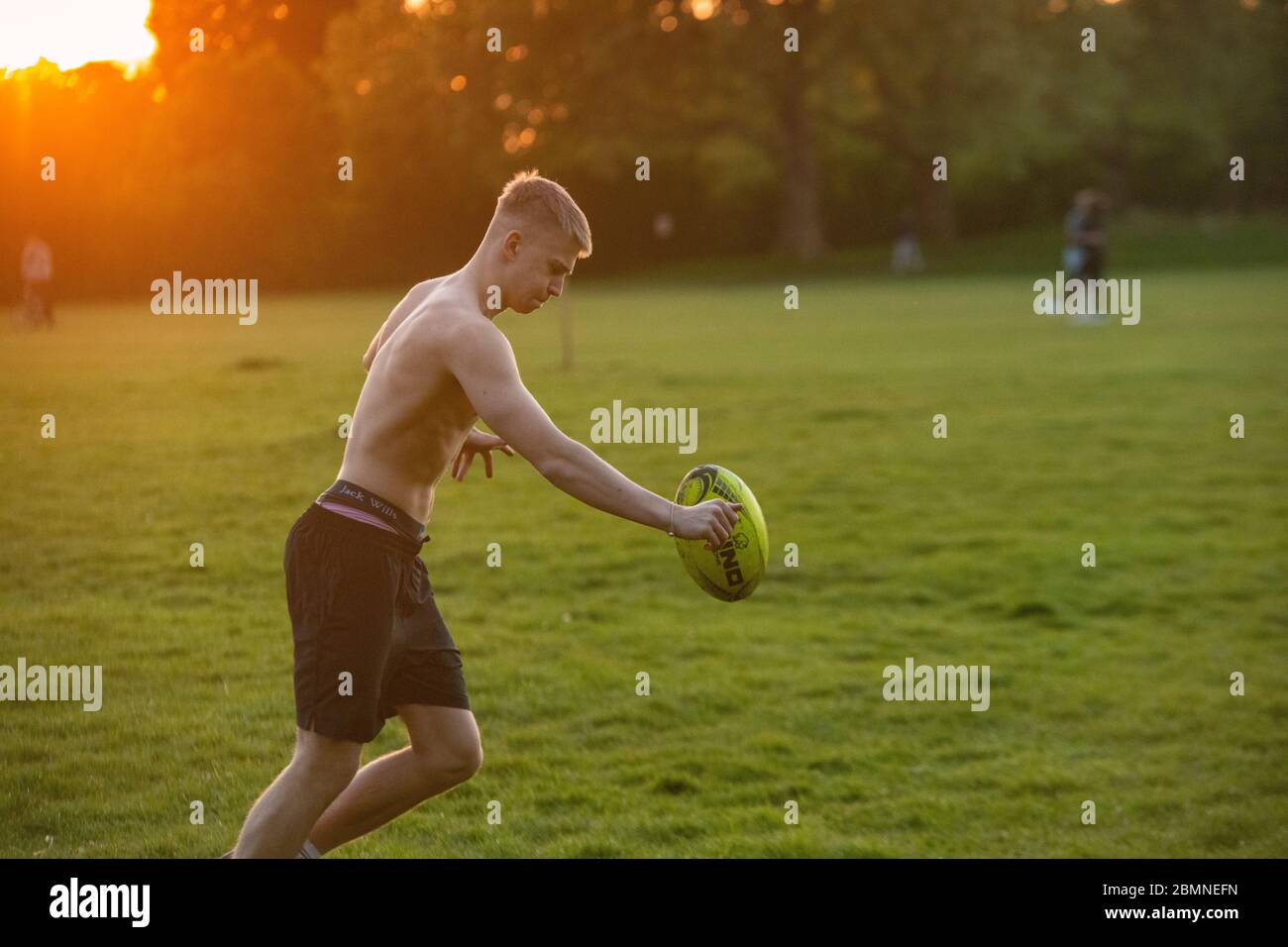 Un teenager muscoloso gioca a rugby al tramonto in un parco londinese Foto  stock - Alamy