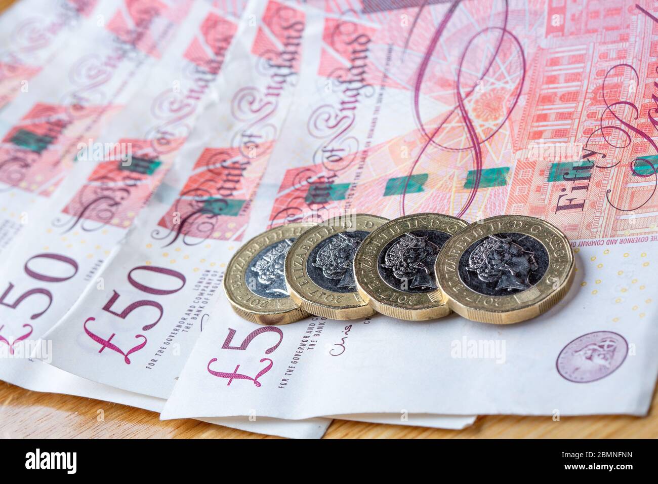 Monete da una libbra che si stendono su banconote da cinquanta libbre, monete da £1 e banconote da £50 inglesi Foto Stock