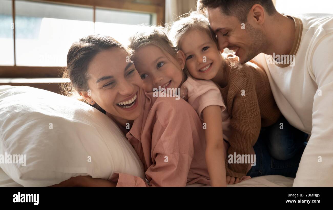 Ritratto genitori felici con due figlie che si abbracciano a letto Foto Stock