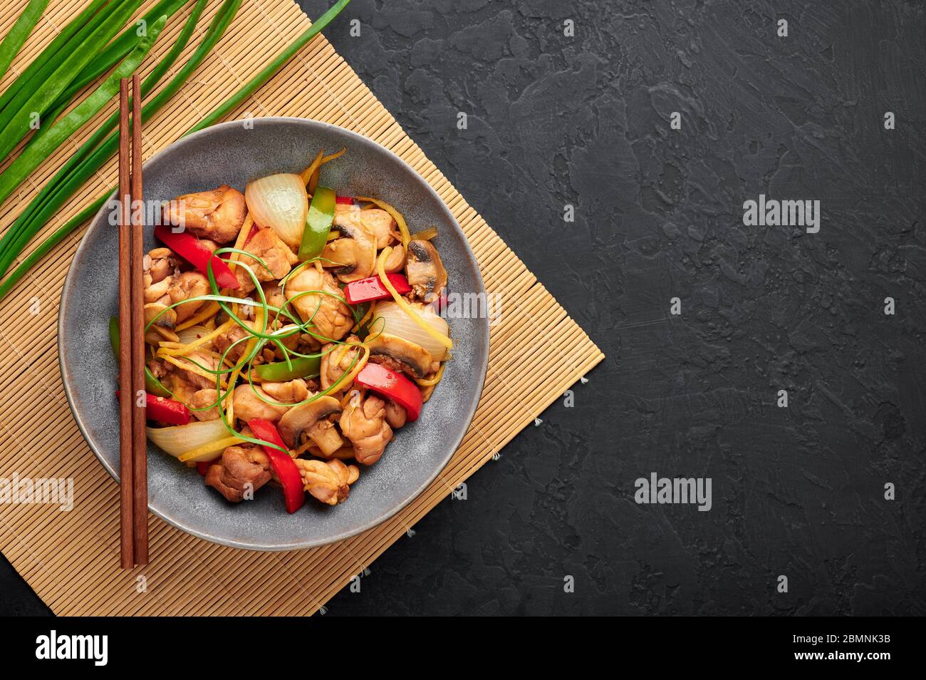 Pollo thai zenzero o Gai Pad King in una ciotola grigia sullo sfondo nero ardesia. Il Gai Pad King è un piatto della cucina thailandese con carne di pollo, strisce di zenzero, onio Foto Stock