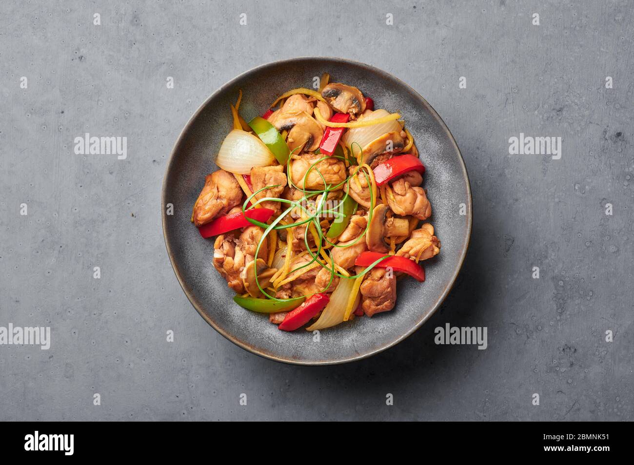 Pollo thai zenzero o Gai Pad King in ciotola opaca grigia sullo sfondo di cemento. Il Gai Pad King è un piatto della cucina tailandese con carne di pollo, strisce di zenzero, o Foto Stock