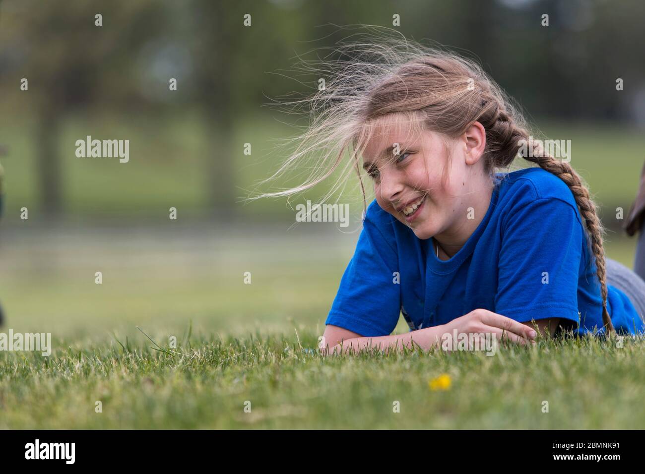 Giovane ragazza sorridente che giace nell'erba. Foto Stock