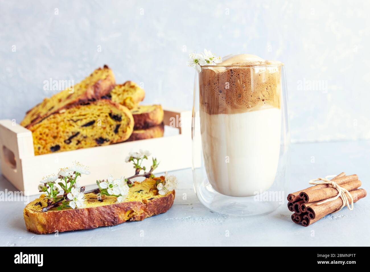 Tazza di caffè alla moda con crema montata e delgona e biscotti italiani su sfondo grigio chiaro. Foto Stock