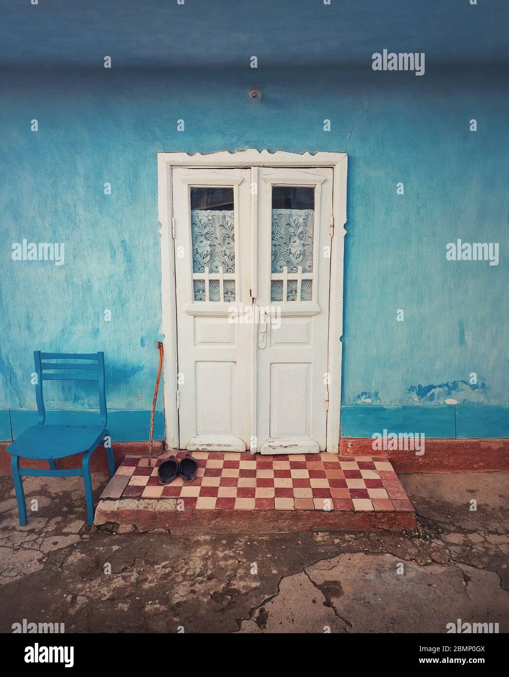 Stampella in legno e un paio di vecchie scarpe sulla soglia, a due passi di una casa rustica. Tradizionale edificio rurale facciata in Moldavia. blu calce dipinta wal Foto Stock