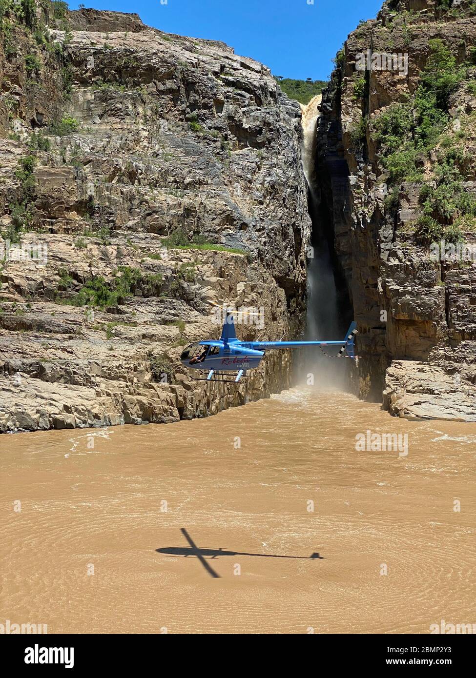 Questo pilota di elicottero si aggira sopra l'acqua accanto alla cascata, in modo che i passeggeri possano ammirare le attrazioni turistiche. Foto Stock