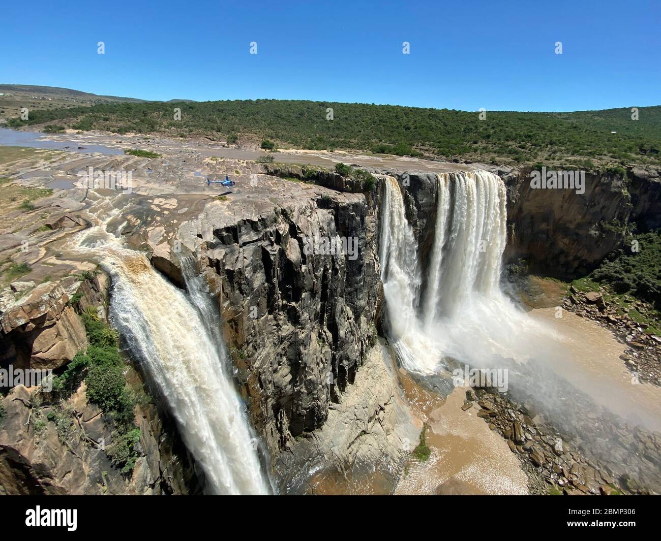 Sopra una cascata un pilota di elicottero cerca di atterrare il suo aereo. E' molto impressionante vedere quanto piccolo l'aereo è vicino alla grande cascata. Foto Stock