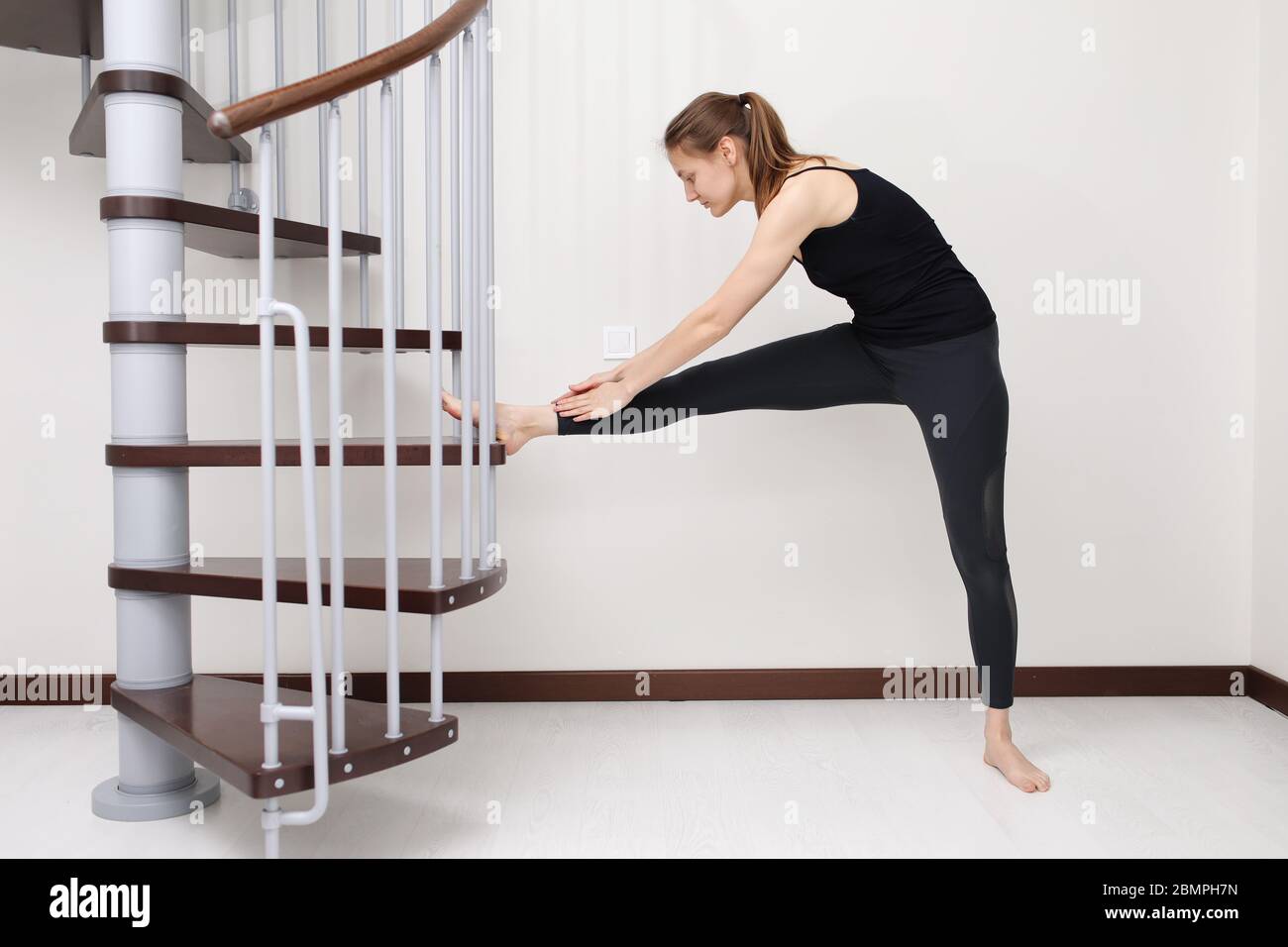 Fa esercizi. Giovane donna con forma sottile del corpo in abbigliamento sportivo per il fitness in casa. Concetto di soggiorno a casa. Foto Stock