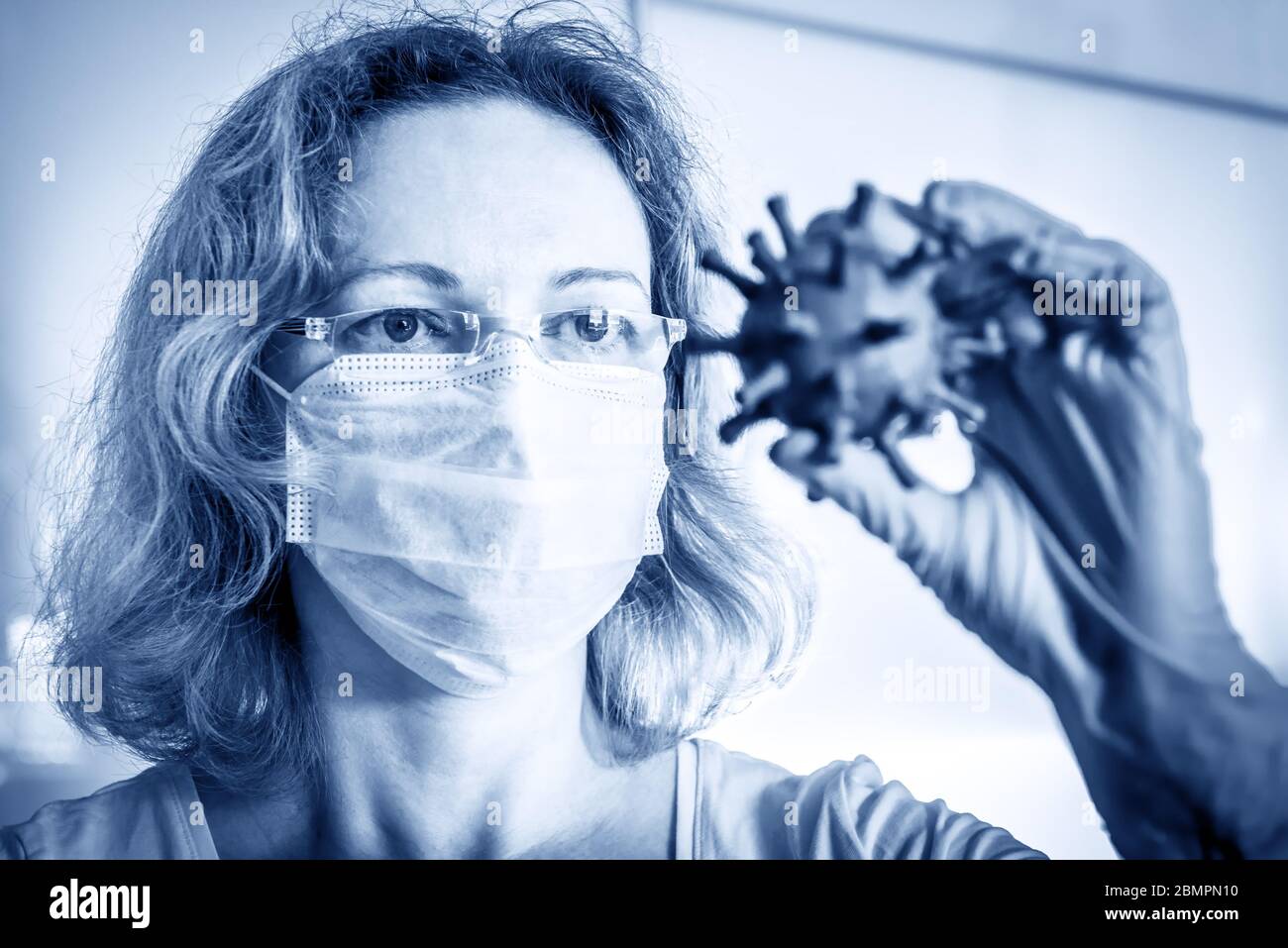 Il ricercatore guarda il coronavirus nella sua mano, il fuoco sugli occhi, COVID-19, la virologia scientifica e concetto di tecnologia, la ricerca medica durante la pandemia di COVID. Foto Stock