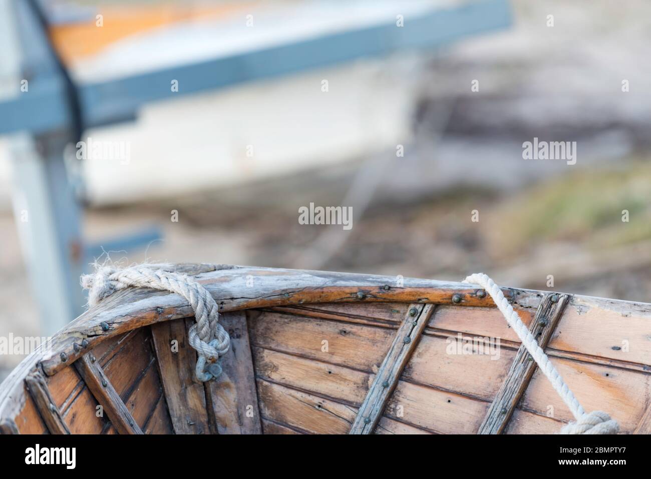 Un primo piano dell'interno della prua di un vecchio rowboat in legno con corda di traino corta legata alla prua Foto Stock