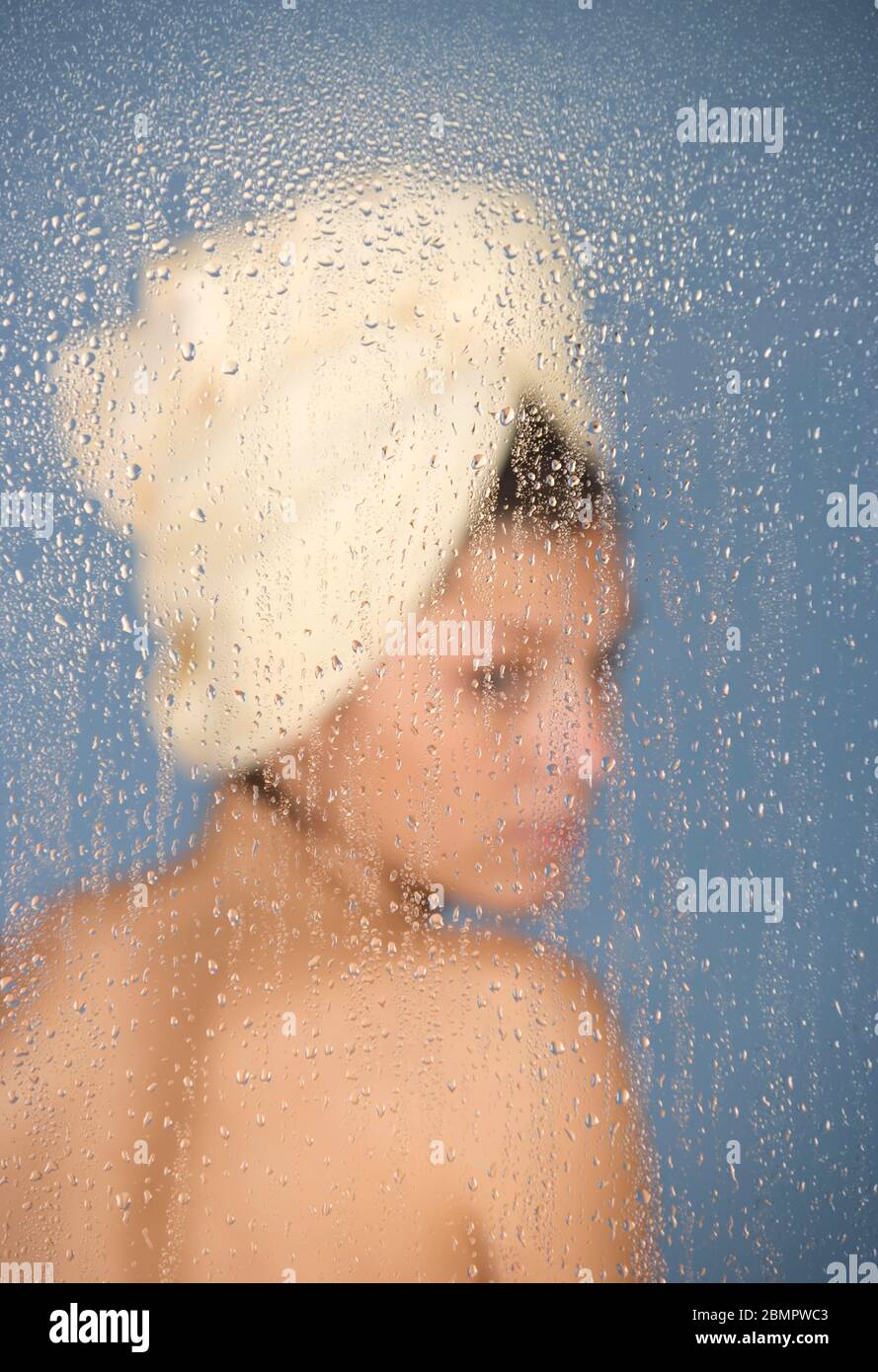 Donna seduta in un bagno di vapore dietro vetro con gocce d'acqua, 24 anni, ritratto, benessere, Germania Foto Stock