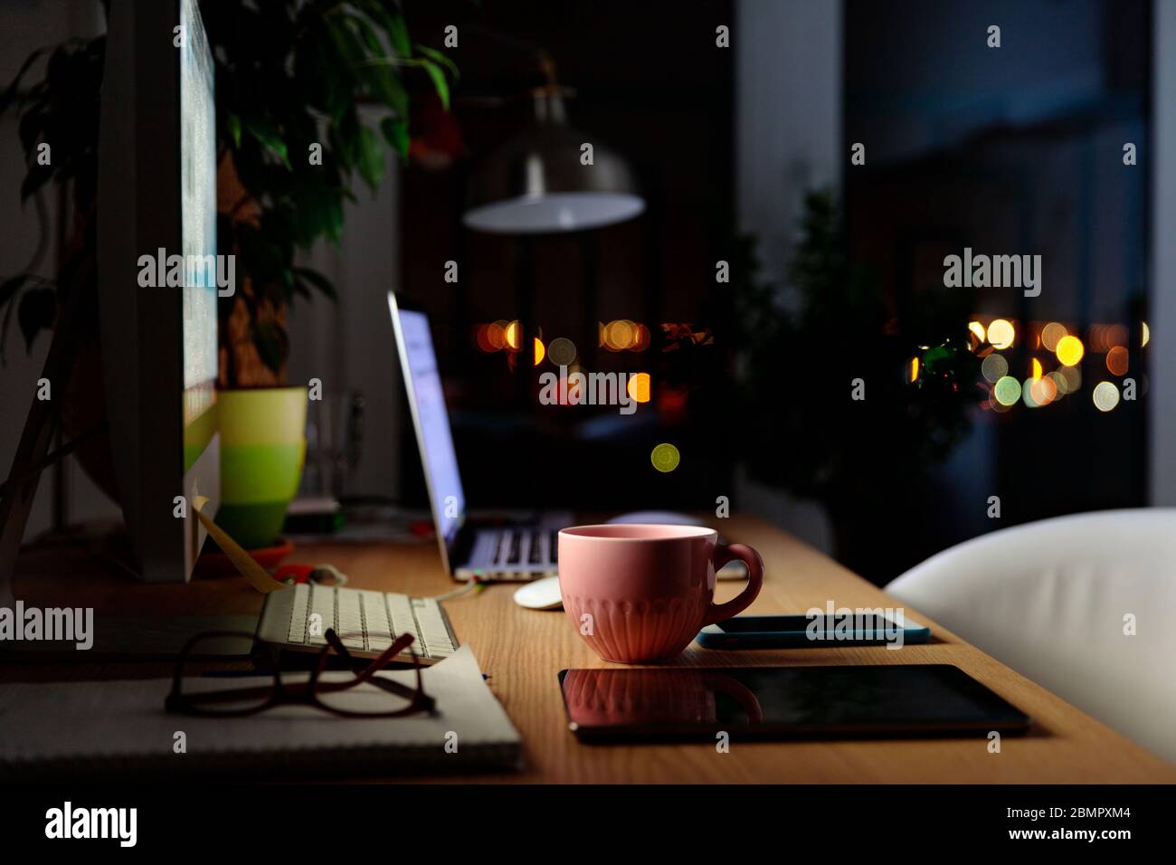 Comodo spazio di lavoro per lavorare a distanza a casa: Tazza di tè, computer, computer portatile, lampada, tablet digitale, smartphone, impianto domestico, notebook, poltrona. Selez Foto Stock