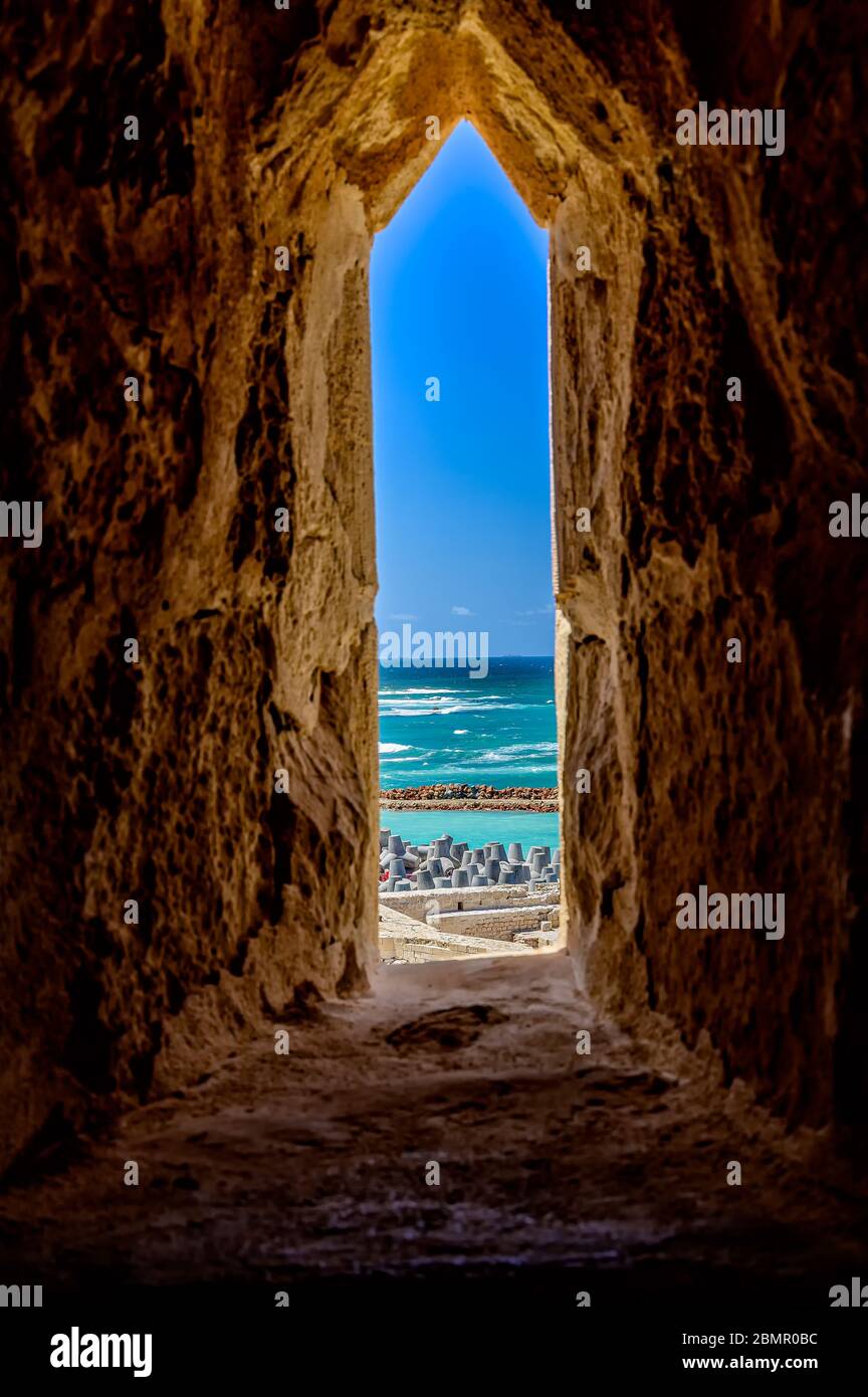 Guardando il Mar Mediterraneo attraverso un'embriura nelle fortificazioni della Cittadella di Qaitbay ad Alessandria Foto Stock