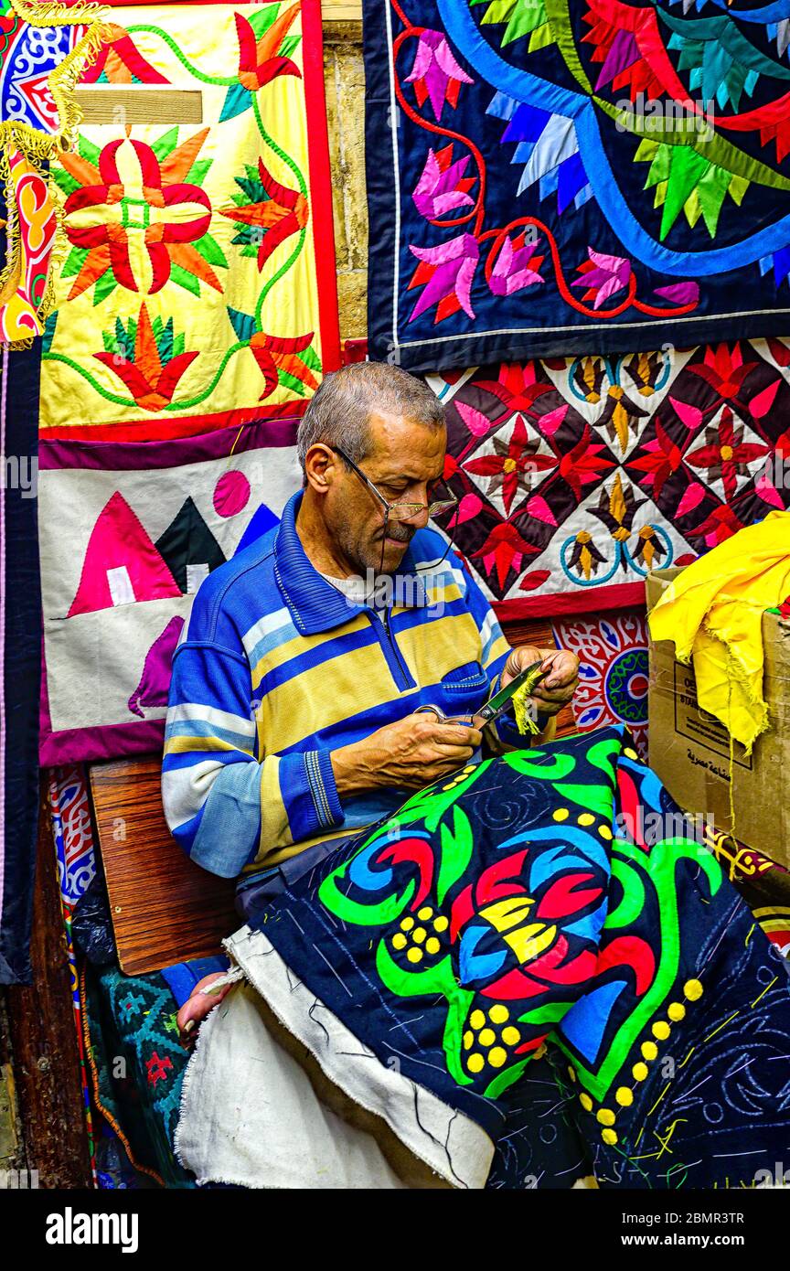 Un tradizionale artigiano egiziano 'Khayameyaa' cucisce a mano su una delle sue trapunte applicate nella sezione di fila dei tentmakers del Souk Khan El Khalili Foto Stock