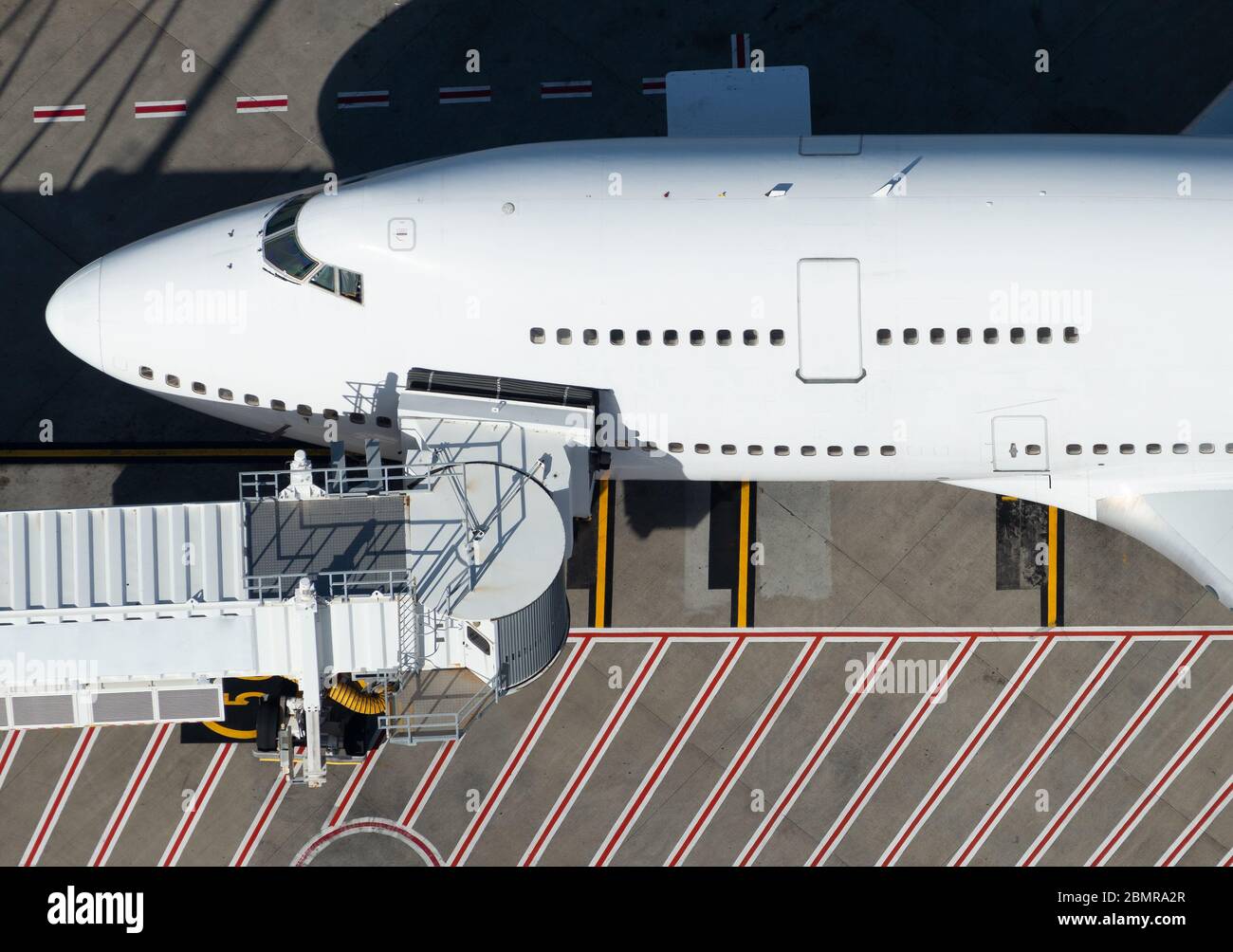 Aereo bianco non identificato a due piani attraccato presso un ponte d'imbarco in un aeroporto internazionale. Vista aerea ravvicinata di un aereo passeggeri. Foto Stock