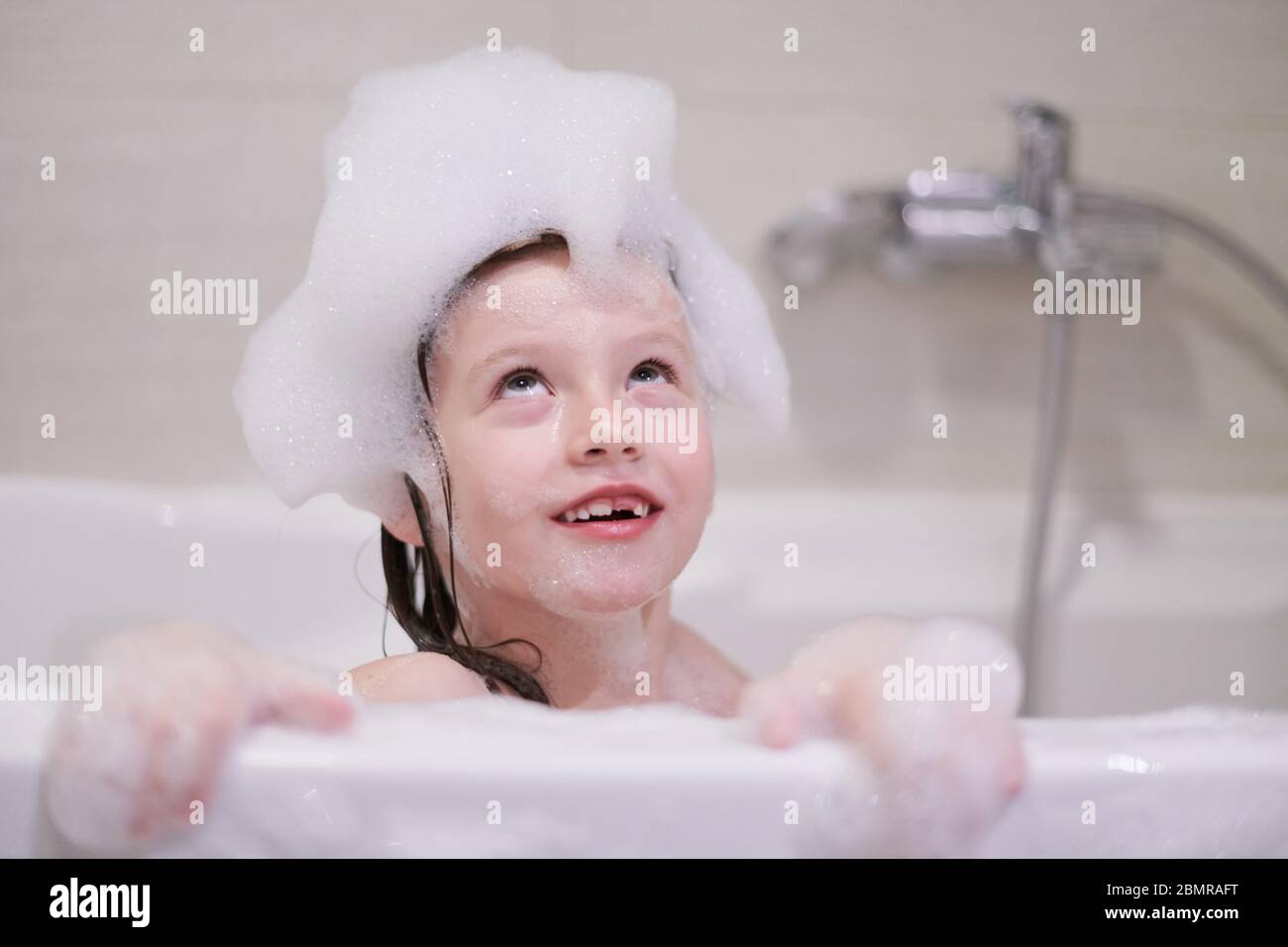 bambina che gioca con schiuma di sapone in bagno durante il coronavirus rimanere a casa quarantena pandemica Foto Stock