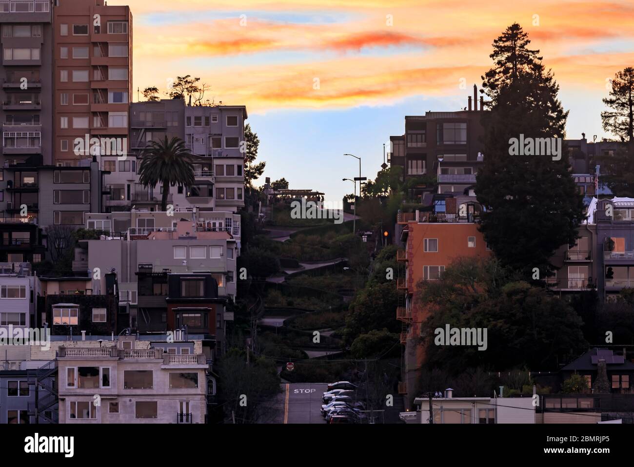 Ammira la famosa Lombard Street a San Francisco, California, con una famosa funivia in cima alla collina e un cielo fiero al tramonto Foto Stock