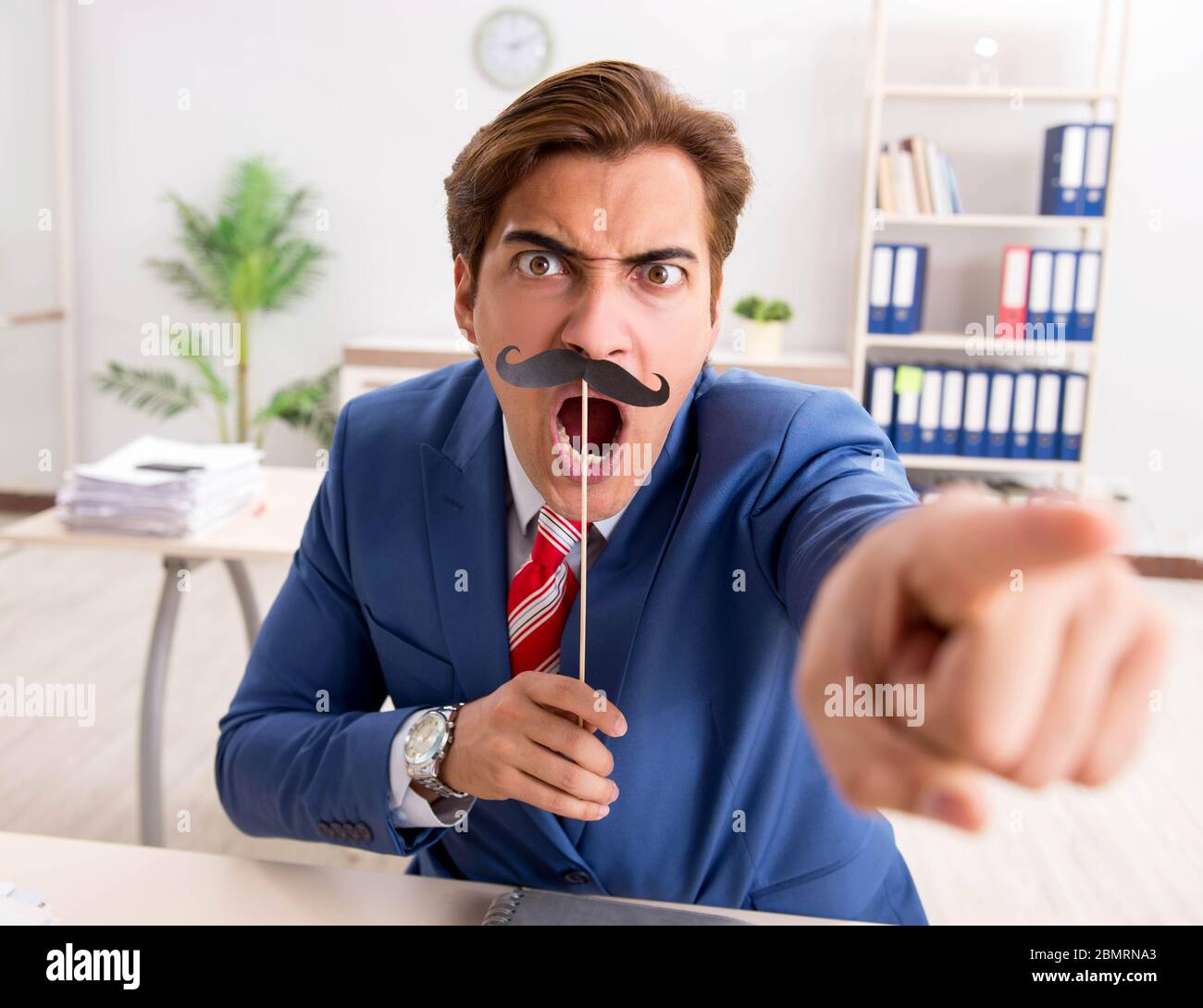 La divertente bisinessman con baffi finti in ufficio Foto Stock
