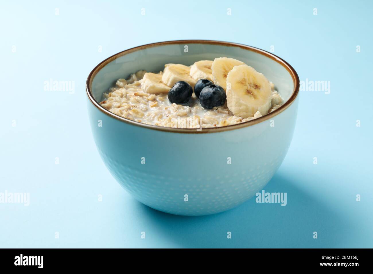 Ciotola con porridge d'avena e frutta su sfondo blu Foto Stock