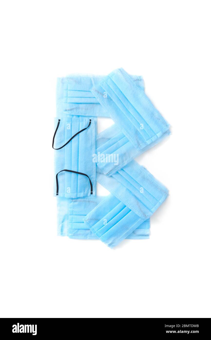 Lettera B realizzata con maschere mediche protettive su sfondo bianco. Foto Stock