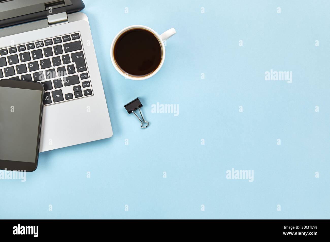 Immagine piatta dello spazio di lavoro blu con laptop, smartphone, caffè e spazio per la copia. Concetto di Hero Header. Vista dall'alto. Foto Stock
