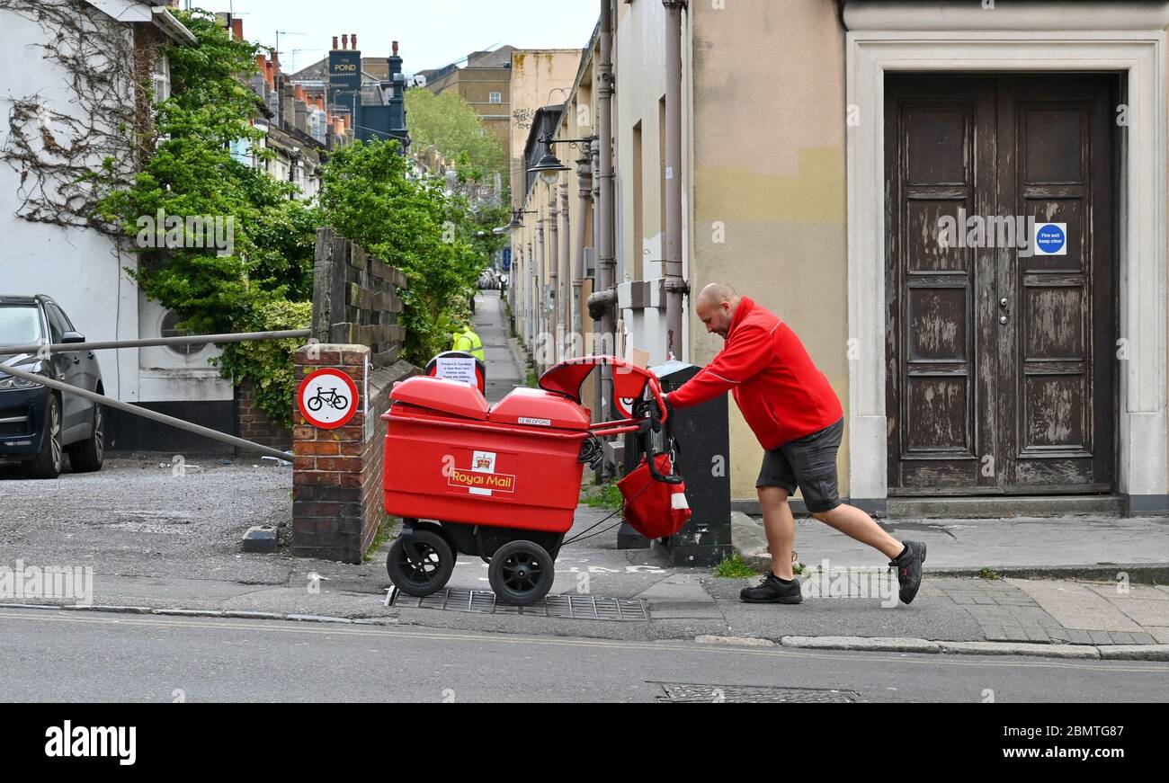 Brighton UK 11 maggio 2020 - UN operatore postale spinge il suo carrello in salita mentre Brighton Street sono ancora tranquille la mattina dopo che il primo Ministro britannico Boris Johnson ha annunciato le nuove linee guida di restrizione di blocco e lo slogan 'Stay Alert ' durante la pandemia COVID-19 coronavirus. : Credit Simon Dack / Alamy Live News Foto Stock