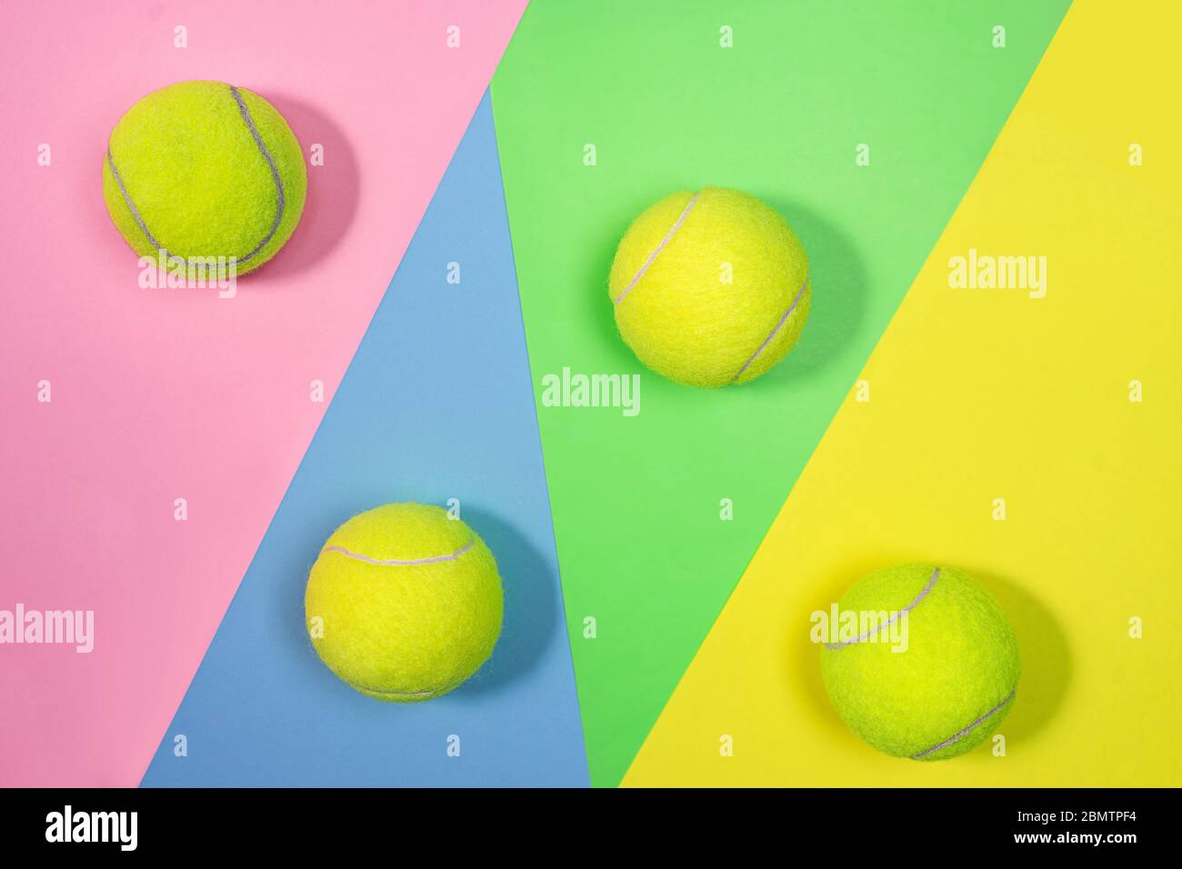 Layout tennis con palle da tennis su sfondo astratto color pastello rosa blu giallo verde multicolore con posto per testo. Concetto sportivo con gioco da tennis. Disposizione piatta, vista dall'alto, messa a fuoco selettiva. Foto Stock