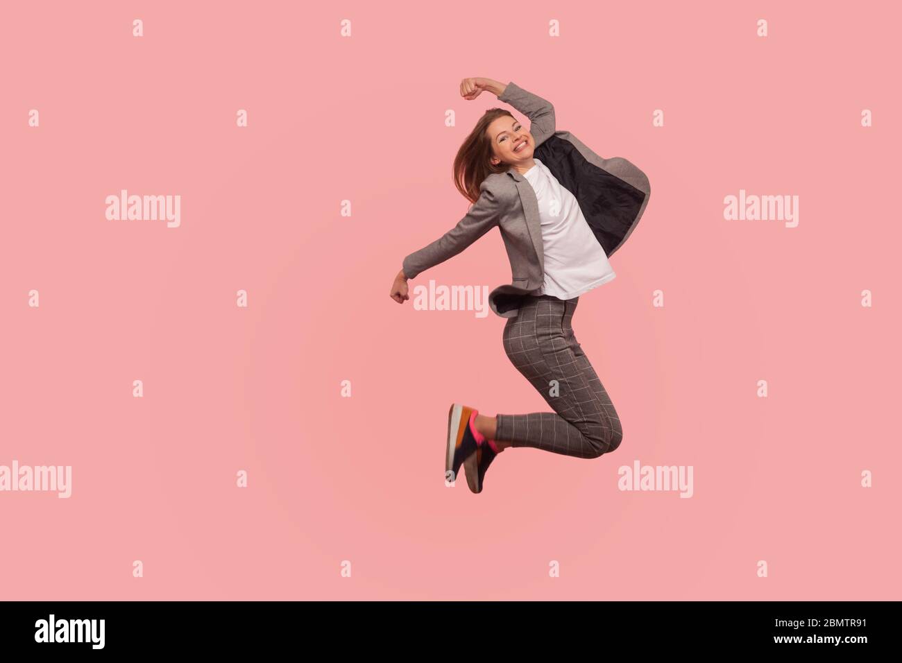 Sono campione! Ritratto di entusiasta e felice businesswoman in tuta elegante jumping spensierato in aria, volare ispirato al successo, celebrare g Foto Stock
