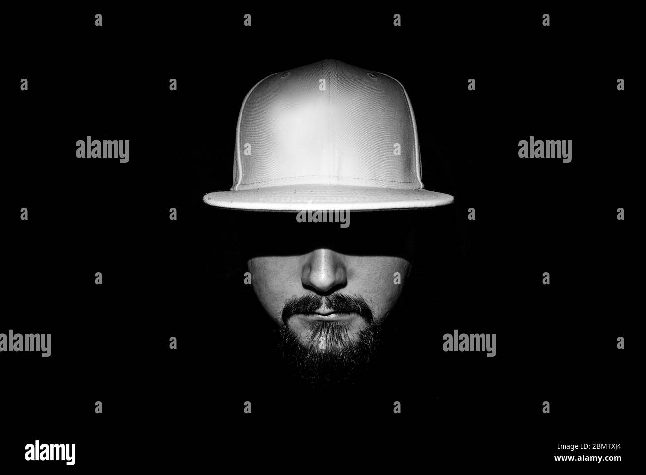 Ritratto monocromatico di un uomo con bassa luminosità e cappuccio bianco Foto Stock