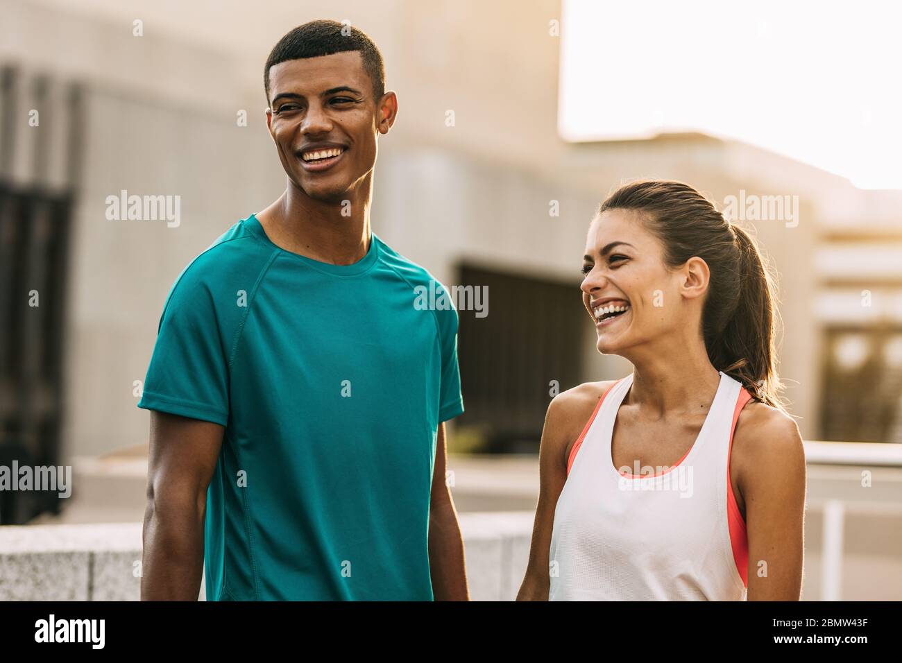 Foto all'aperto di due persone che prendono una pausa dopo una sessione di allenamento. Uomo e donna in piedi in città e rilassarsi dopo un allenamento. Foto Stock