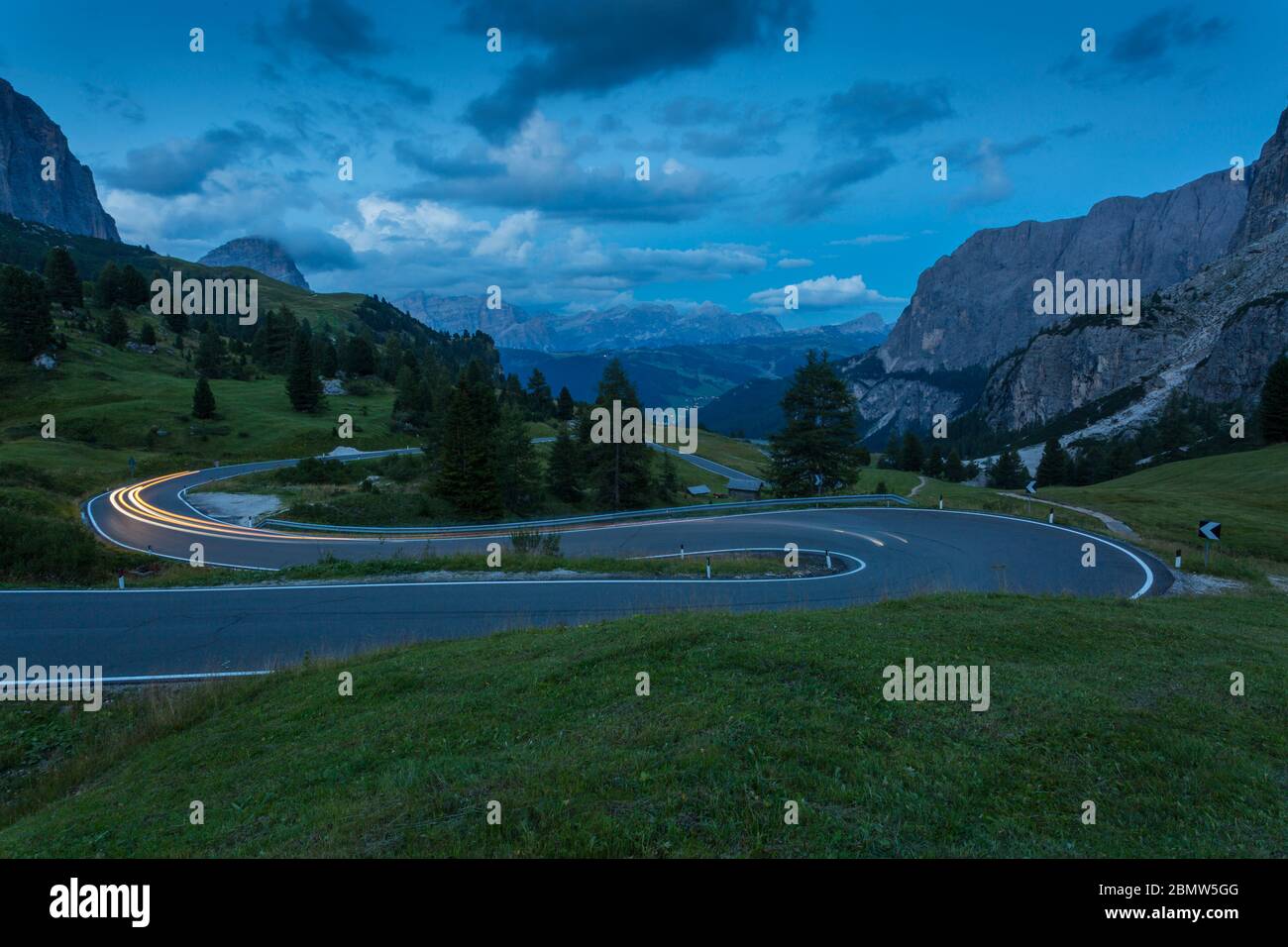 Auto trail luci sul Passo Pordoi con sfondo di montagne al tramonto, Provincia Autonoma di Bolzano Alto Adige, Dolomiti italiane, Italia, Europa Foto Stock