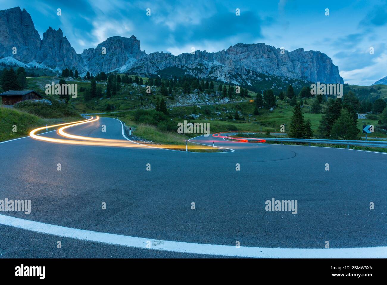 Auto trail luci sul Passo Pordoi con sfondo di montagne al tramonto, Provincia Autonoma di Bolzano Alto Adige, Dolomiti italiane, Italia, Europa Foto Stock