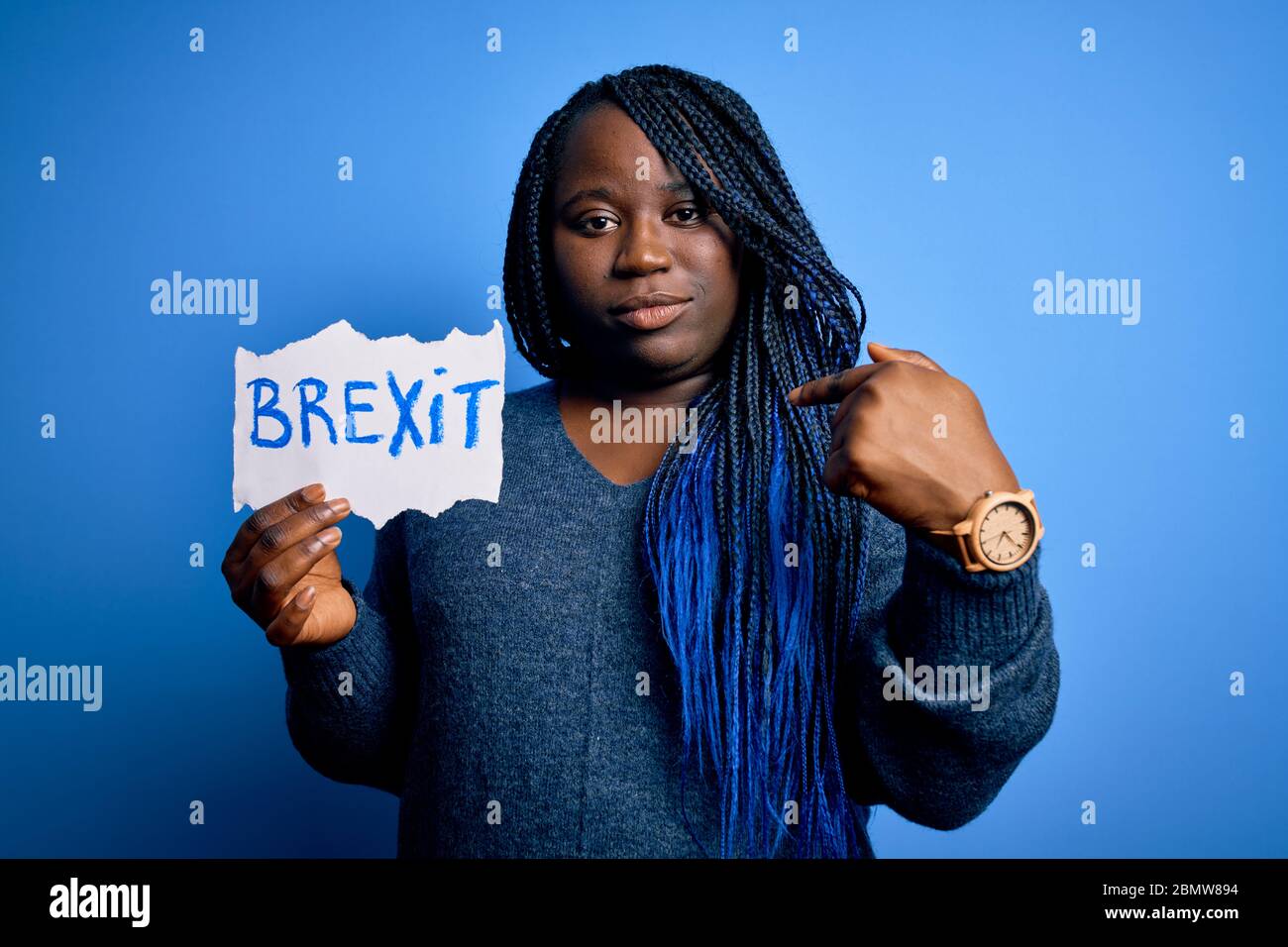 Giovane african american più donna con trecce che tiene carta con messaggio brexit con la faccia a sorpresa che punta il dito a se stesso Foto Stock