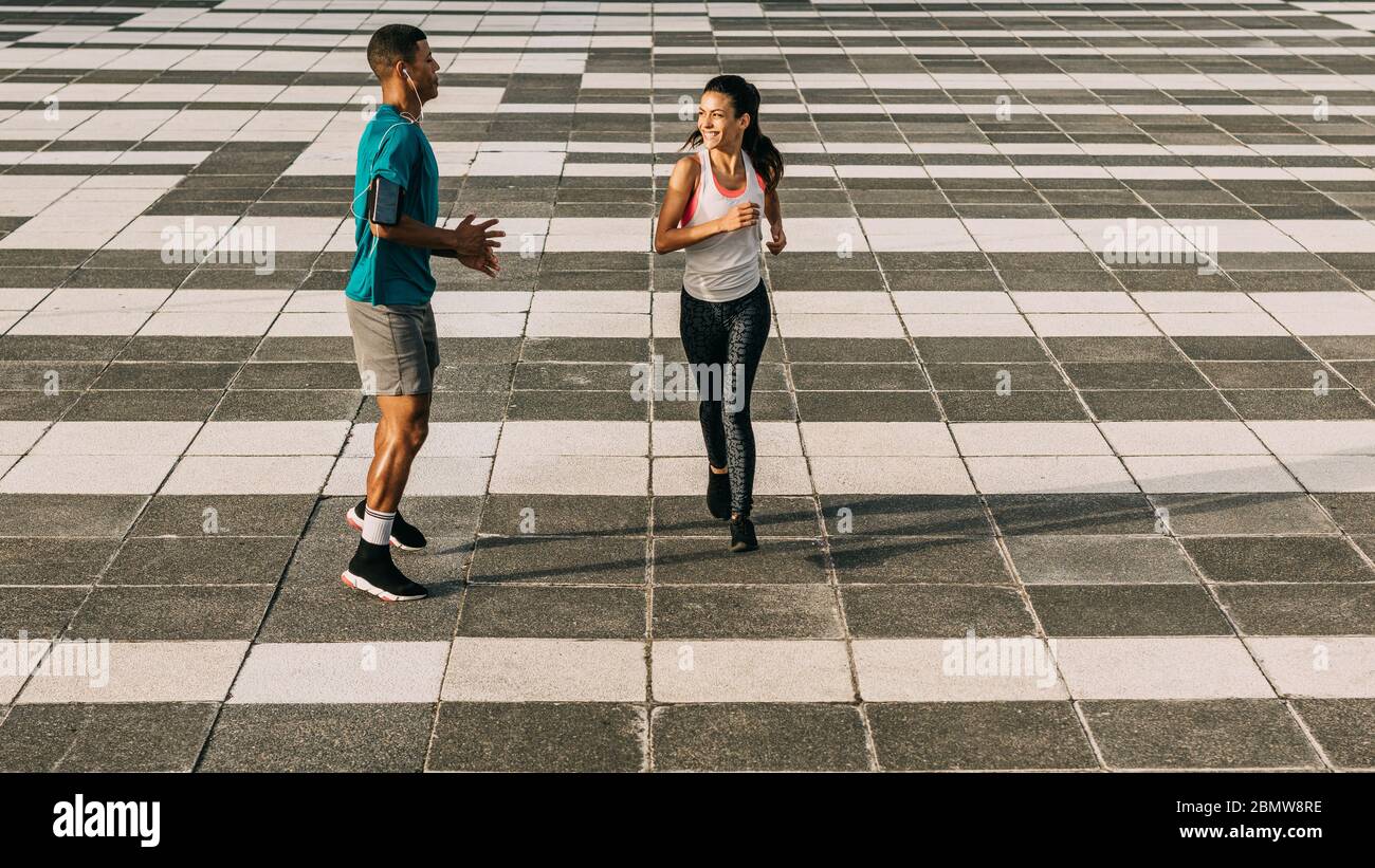 Felice uomo e donna che corrono insieme in città. Coppia in allenamento sportivo insieme in città. Foto Stock