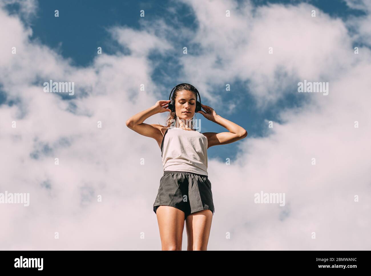 Inquadratura ad angolo basso di una donna che si adatta alle cuffie prima di andare a correre la mattina Foto Stock
