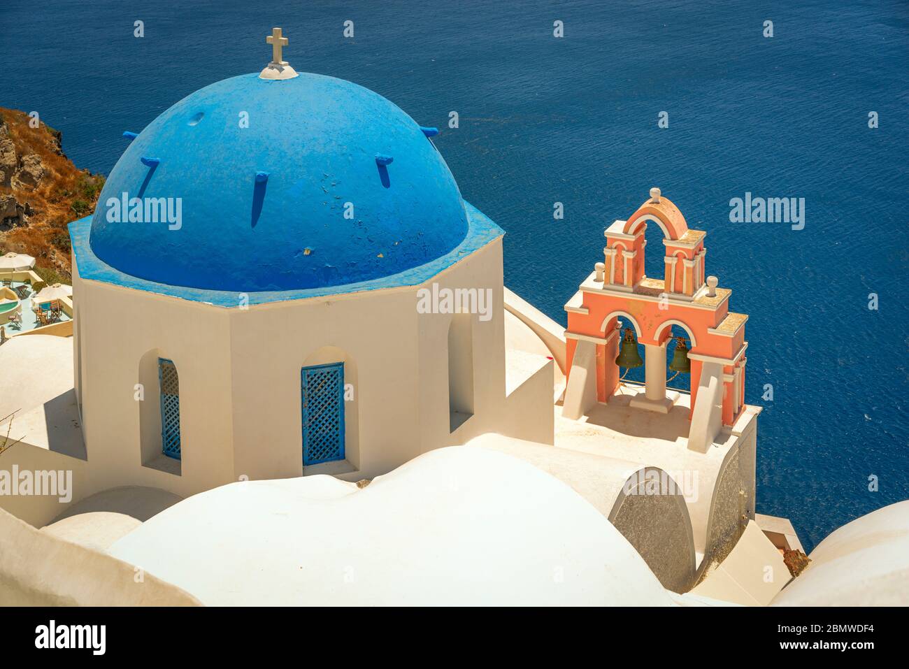 Si affaccia su una idilliaca chiesa a cupola blu e l'annesso campanile ornato che è tipico dell'isola greca di Santorini. Foto Stock
