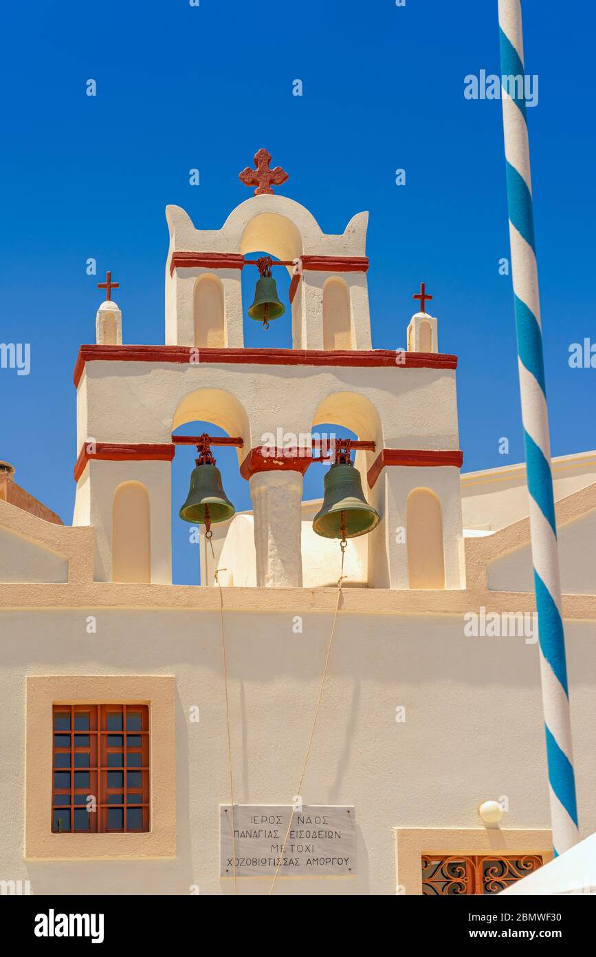 Bella vecchia belferia a Oia, Santorini, dipinta di crema e rosso contro un cielo blu chiaro nella giornata di sole Foto Stock