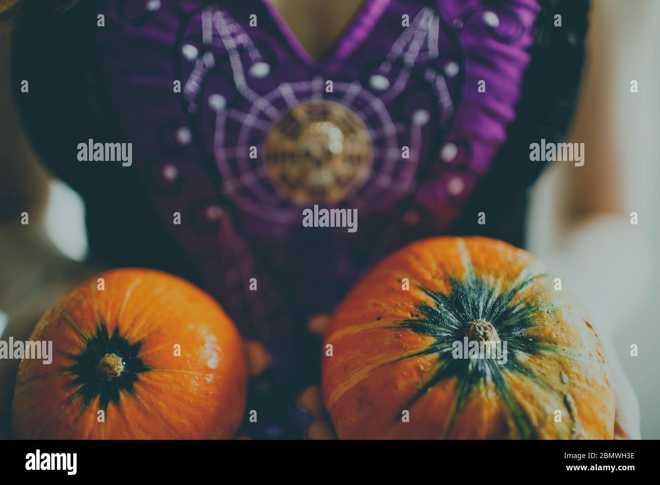 Una ragazza in un vestito festivo che tiene le zucche per Halloween. Foto Stock