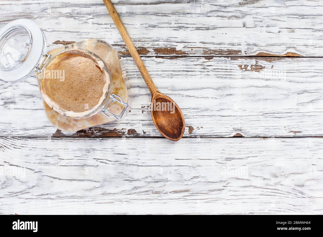Antipasto attivo vivo di pasta di grano integrale con un cucchiaio di legno su un tavolo/sfondo bianco rustico in legno con spazio libero per il testo immagine ripresa dall'alto Foto Stock