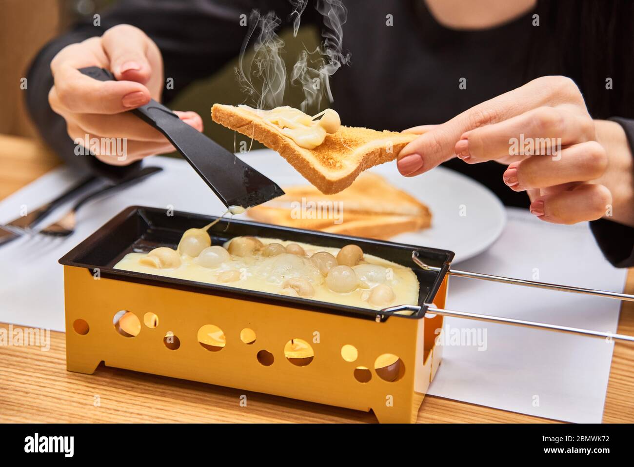 cibo svizzero. raclette di formaggio con funghi su coupélles - padella speciale piccola per una raclette Foto Stock