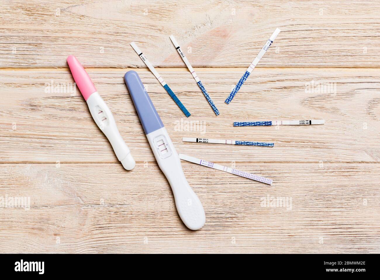 Prova di gravidanza colorata su sfondo in legno, vista dall'alto con spazio per copia. Foto Stock