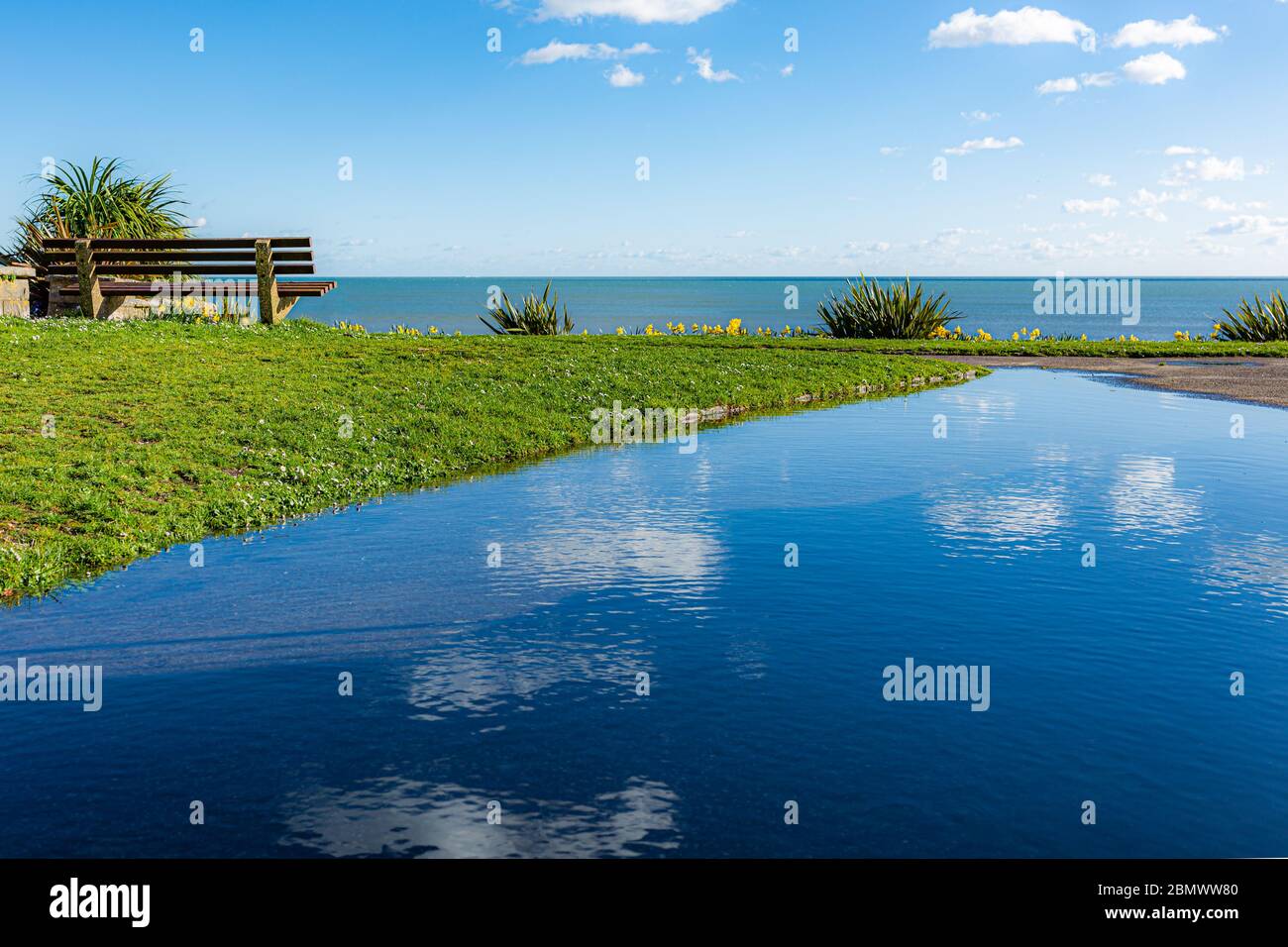 Foto paesaggistica del cielo blu riflessa in un grande pouddle sul punto di vista pubblico che si affaccia sul mare Foto Stock