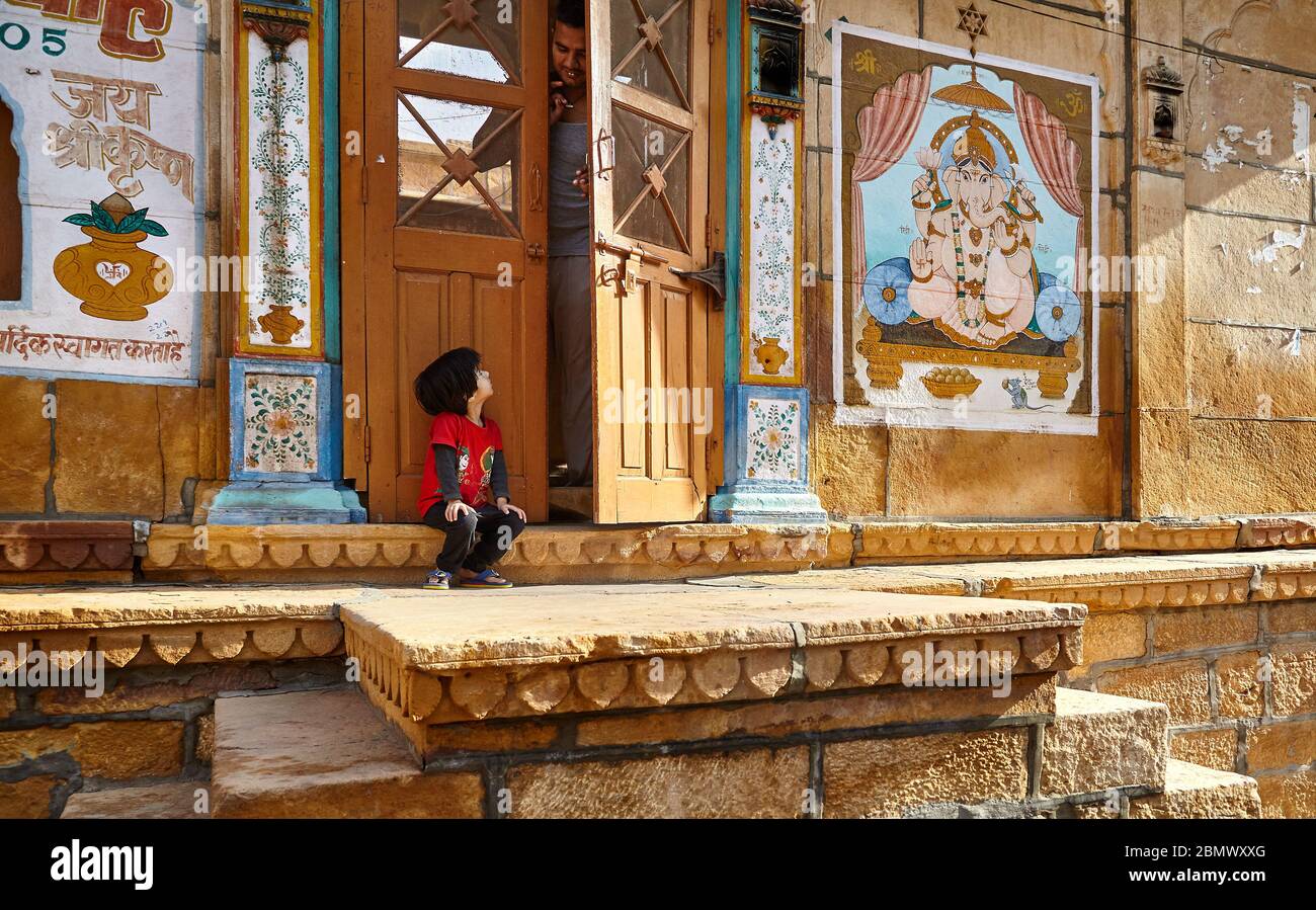 JAISALMER, India - 14 Marzo 2015: il giovane ragazzo è guardando al suo padre nella porta alla vecchia casa in città di Jaisalmer, India. Jaisalmer è una meta molto popolare tra i t Foto Stock