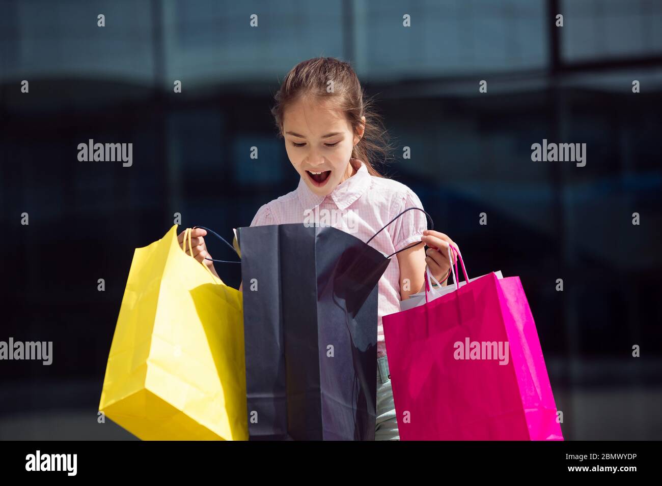 Vendita, consumismo: Bambina piccola ragazza giovane shopaholic con borse shopping vicino centro commerciale Foto Stock