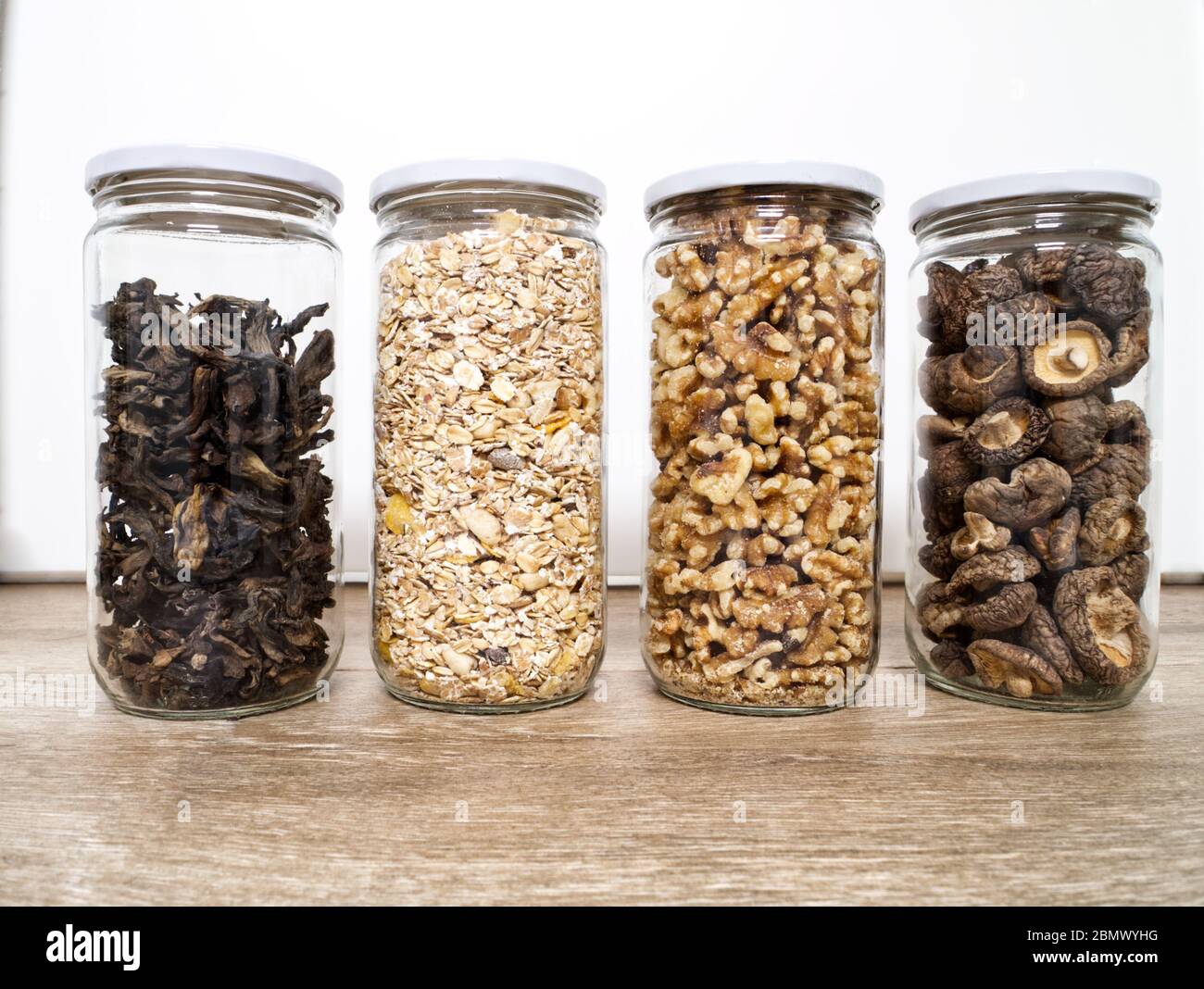 Stoccaggio di alimenti sfusi in vasetti di vetro: Funghi selvatici secchi, muesli e noci. Concetto di zero sprechi. Foto Stock