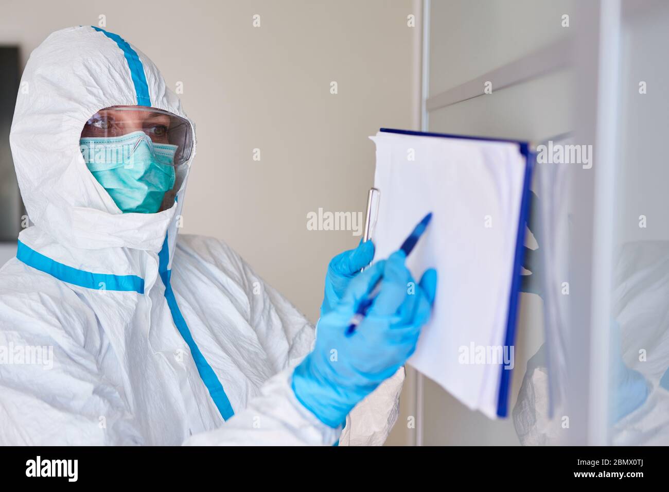 Personale infermieristico in abbigliamento protettivo con lista visitatori a causa di virus corona in casa di cura o clinica Foto Stock