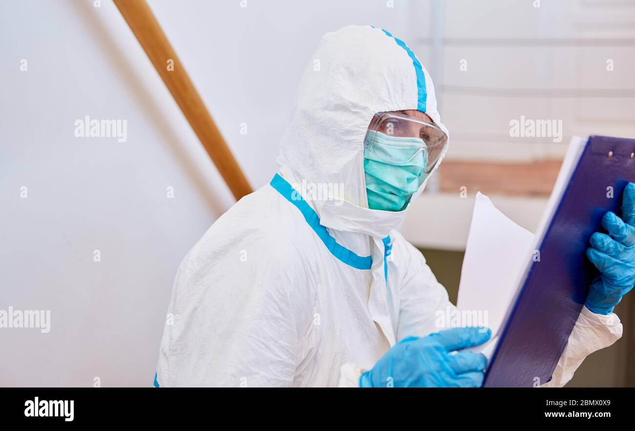 Lo scout di Containtment in indumenti protettivi guarda alla lista per il tracciamento del contatto in pandemia di coronavirus Foto Stock