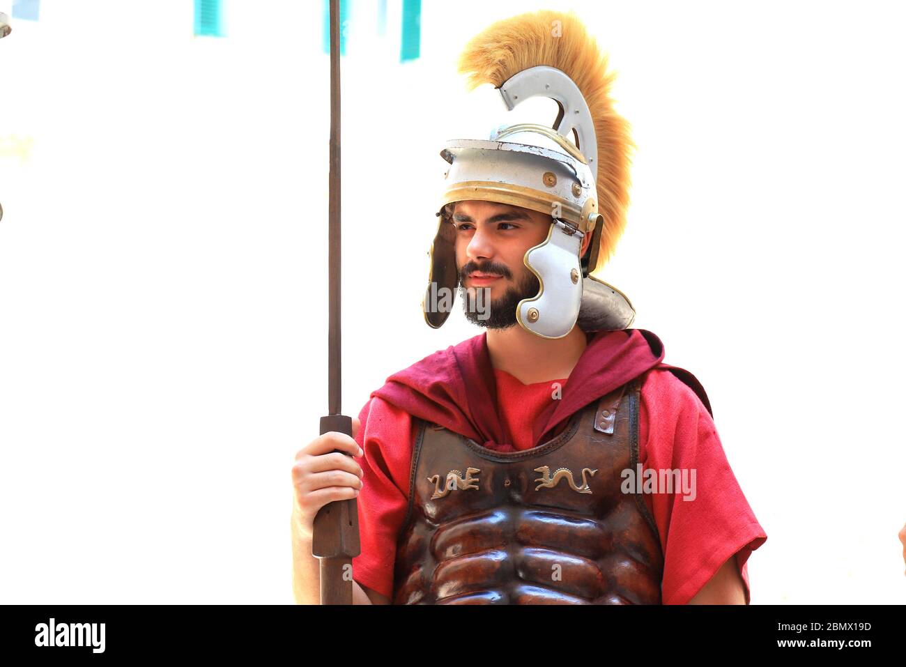 Un giovane uomo barbuto in uniforme rossa di legionario romano, in un casco metallico, tunica e con una lancia si trova nella storica città croata Spalato Foto Stock