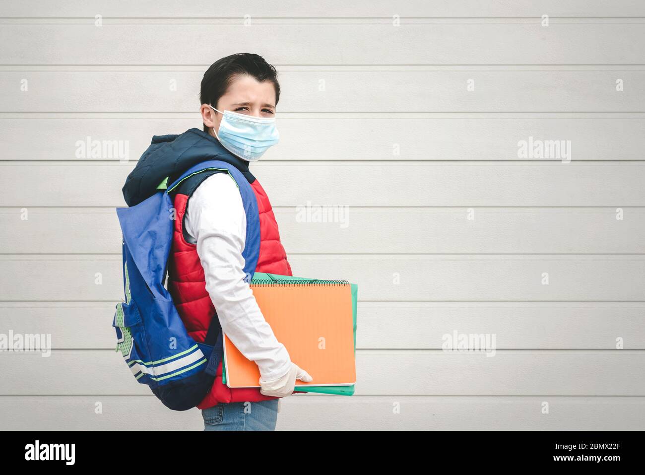 covid-19, ritratto di un bambino con maschera medica e zaino andare a scuola all'aperto Foto Stock