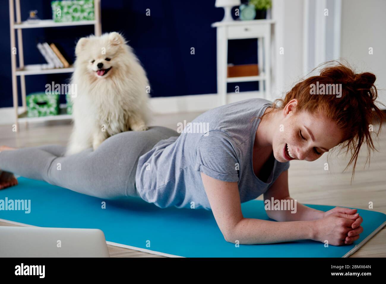 Donna che fa alcuni esercizi di yoga con il suo cane a casa Foto Stock